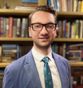 Kenneth Gatten in blue suit in front of bookshelves